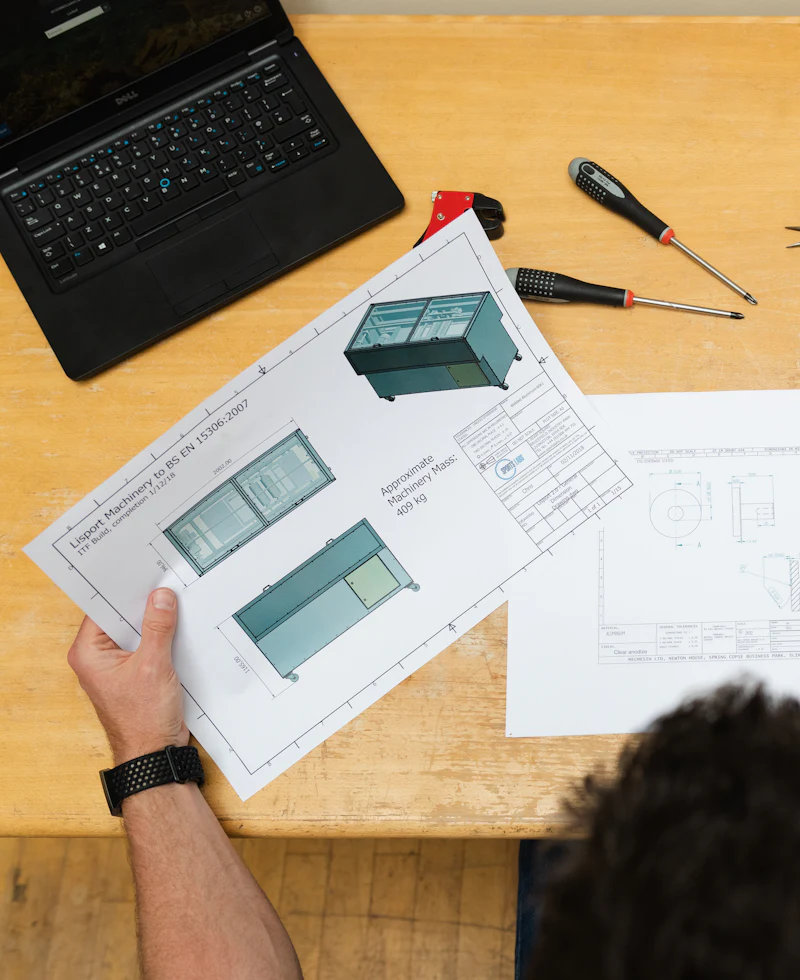 Engineer reviewing part drawings at a workbench